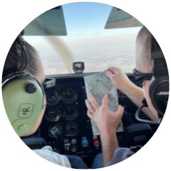 ֻ̳cadets in the aviation club fly in a plane over post, reviewing a map.