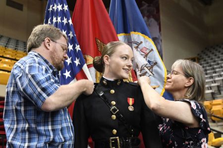 Female cadet at ֻ̳receives US Marine Corps insignia pins from family during Commissioning