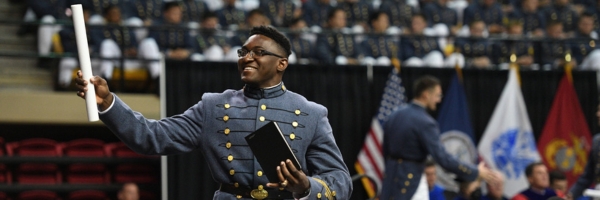 Cadet raises diploma towards a cheering crowd in Cameron Hall at ֻ̳during Commencement.